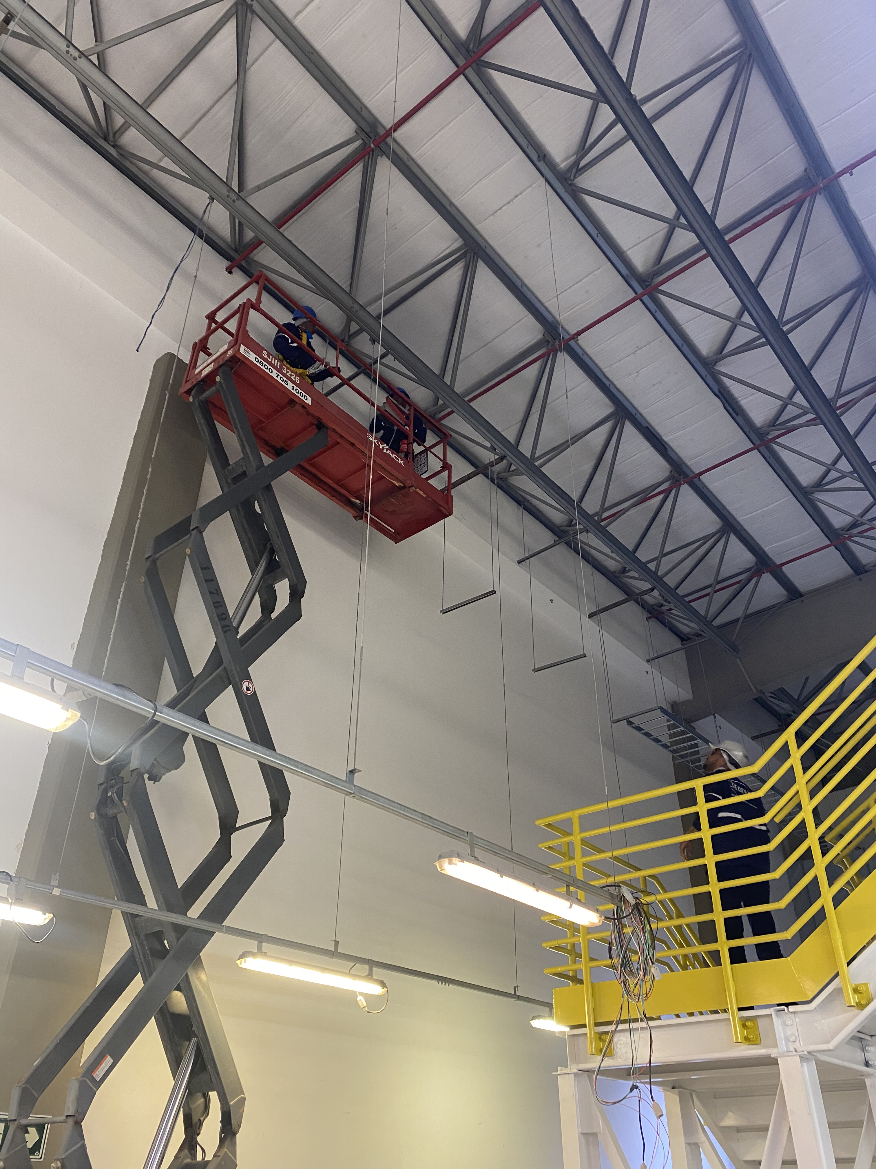 Equipe instalando circuitos de iluminação em galpão industrial